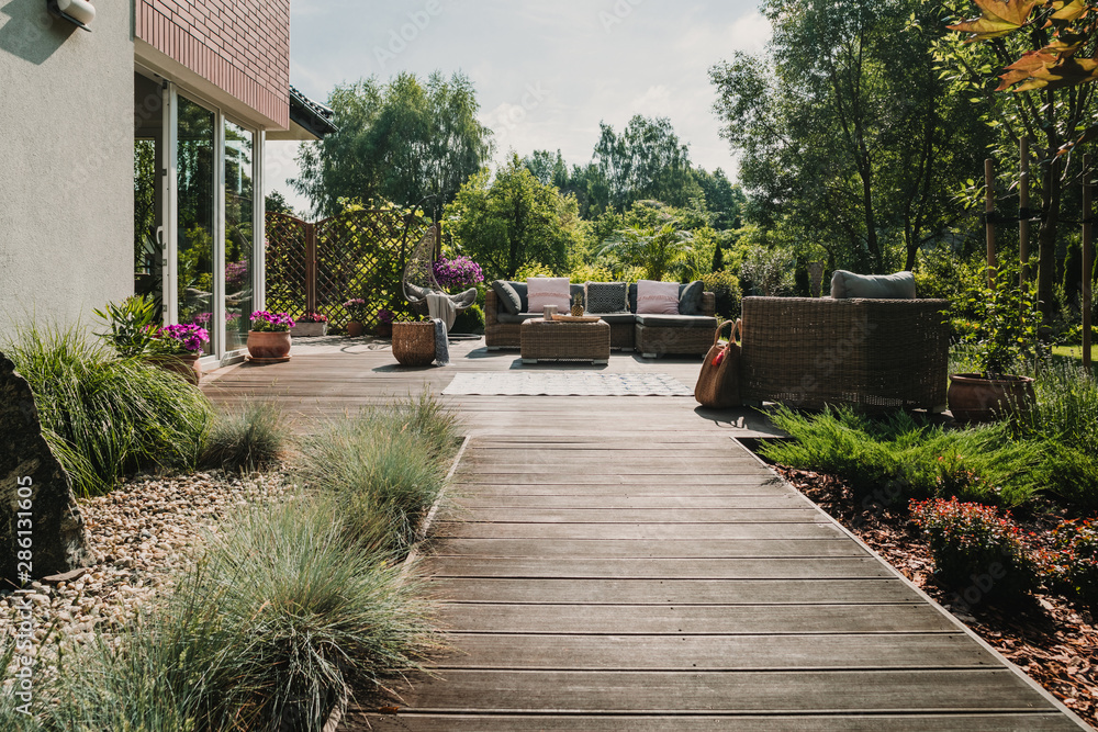 Wooden path to terrace in the garden with trendy garden furniture Wooden path to terrace in the garden with trendy garden furniture