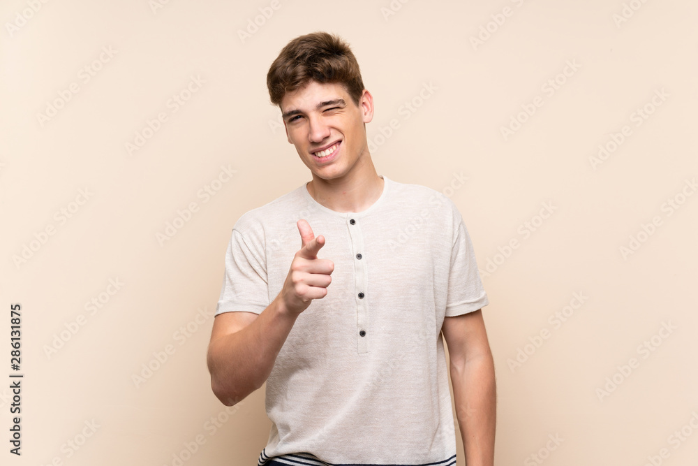 Handsome young man over isolated background points finger at you Handsome young man over isolated background points finger at you