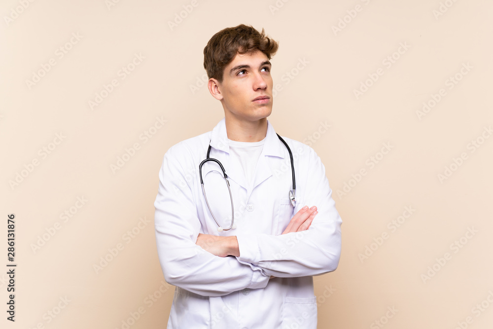 Handsome doctor young man over isolated wall looking up while smiling Handsome doctor young man over isolated wall looking up while smiling