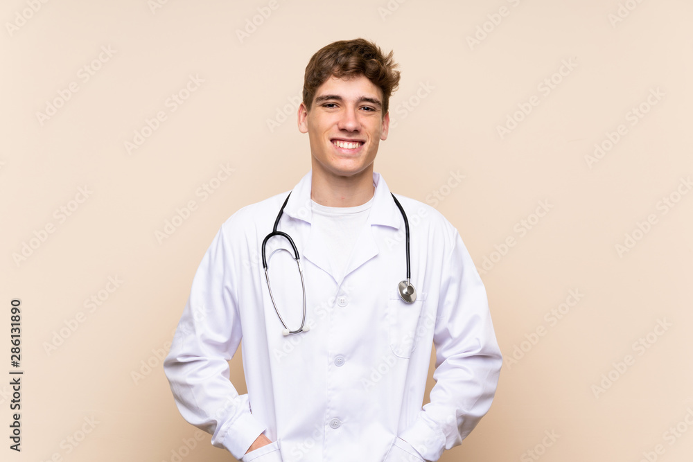 Handsome doctor young man over isolated wall smiling a lot Handsome doctor young man over isolated wall smiling a lot