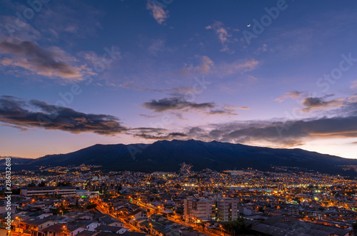 Cityscape of Quito city at sunset with the mighty peaks of the Pichincha volcano, Andes mountains, Ecuador.