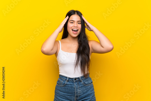 Young teenager Asian girl over isolated yellow background with surprise expression © luismolinero