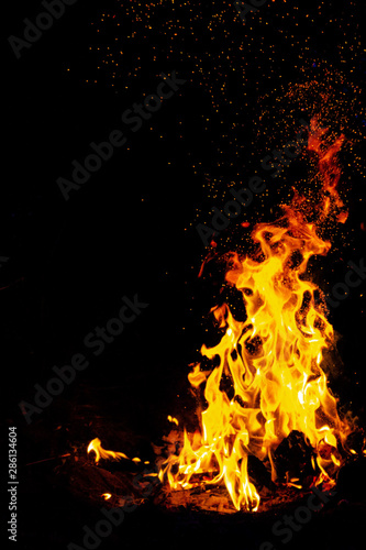 bonfire with sparks burns brightly on a black background at night in a travelers camp