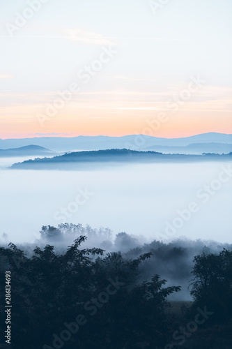 view of sunrise over the mountains mist and clouds under peaks © phpetrunina14