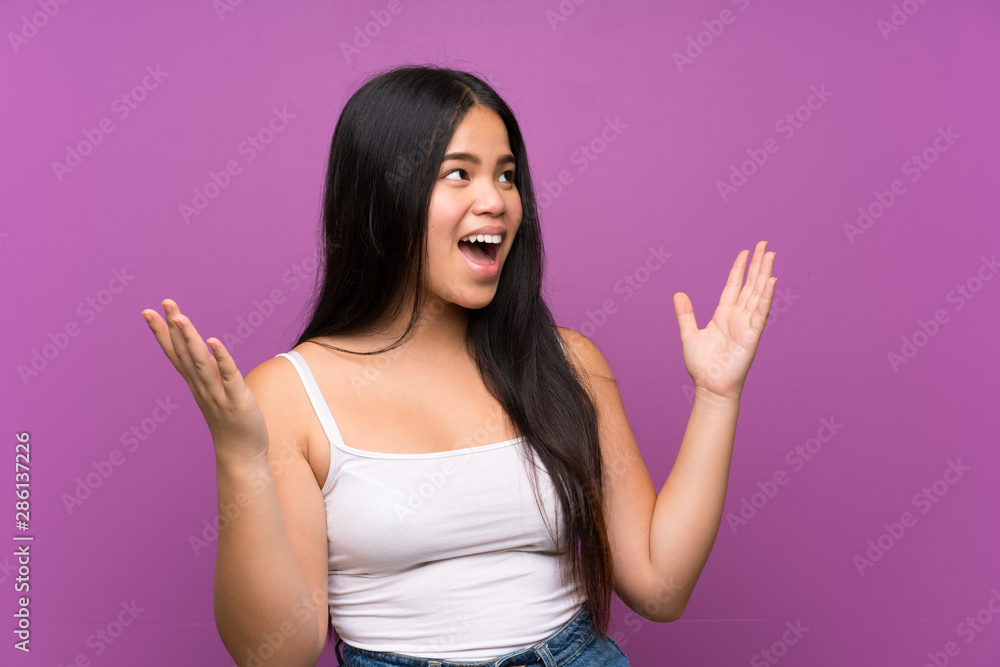 Young teenager Asian girl over isolated purple background with surprise facial expression Young teenager Asian girl over isolated purple background with surprise facial expression