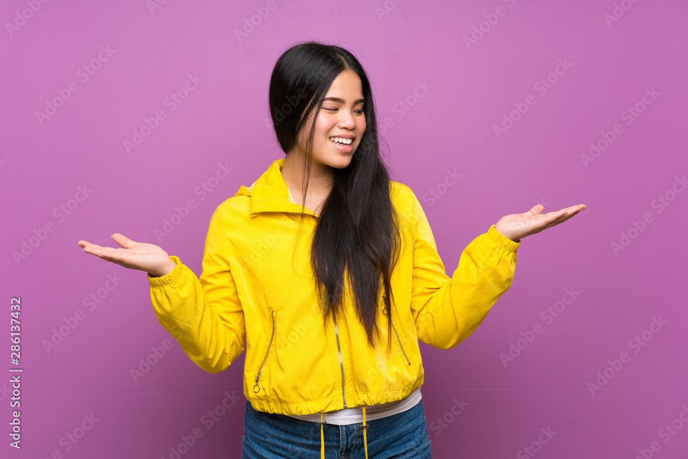 Young teenager Asian girl over isolated purple background holding copyspace with two hands Young teenager Asian girl over isolated purple background holding copyspace with two hands