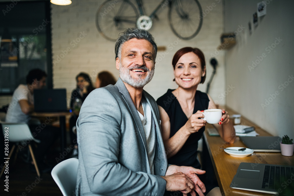Obraz premium Man and woman having business meeting in a cafe, using laptop.