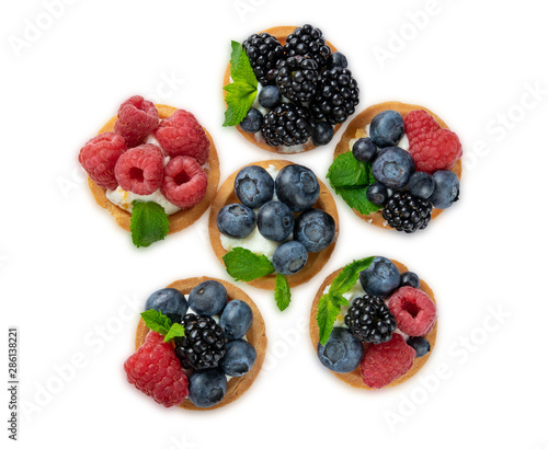 Tartlet with berries of raspberry, bilberry, blackberry, blueberry isolated on white background. Cake with berries, mint leaf and cheese cream. View from above