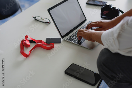 Businessman s hands typing on laptop keyboard in morning light .