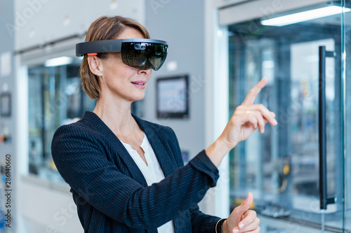 Businesswoman wearing AR glasses in a modern factory photo