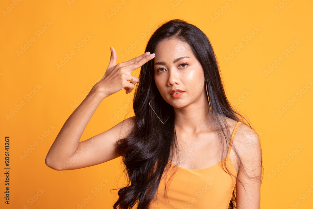 Beautiful young Asian woman holding fingers in gun gesture. Beautiful young Asian woman holding fingers in gun gesture.