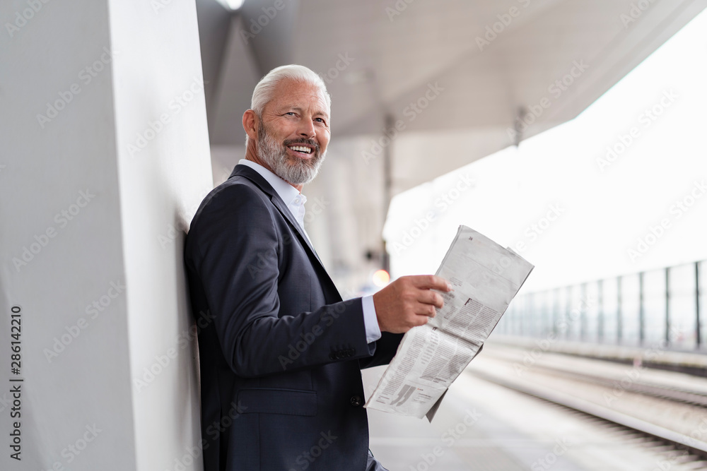 Happy mature businessman with newspaper at the station platform Happy mature businessman with newspaper at the station platform