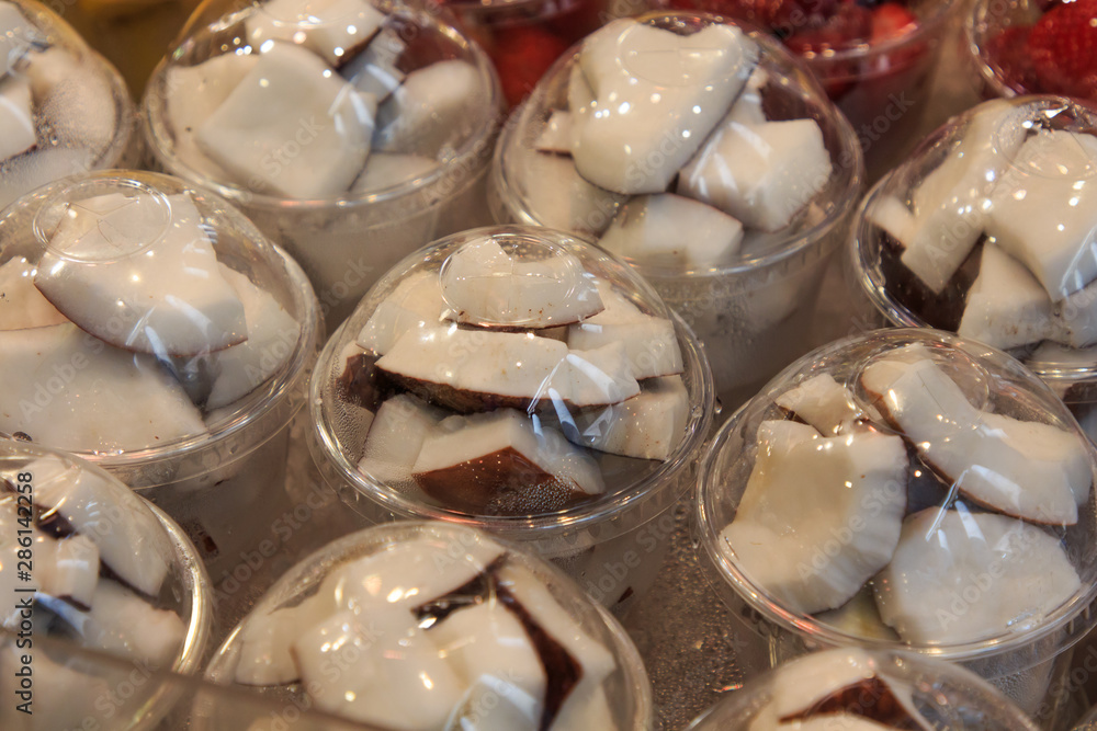 Coconut sliced put in covered plastic cups in Mercado de la Boqueria. Food concept Coconut sliced put in covered plastic cups in Mercado de la Boqueria. Food concept
