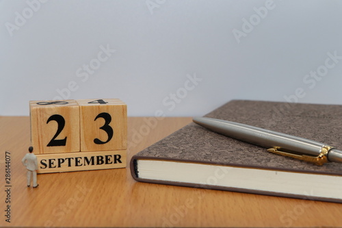 September  23, a calendar photo from the wood The table top consists of a book and pen that is ready to use. White background