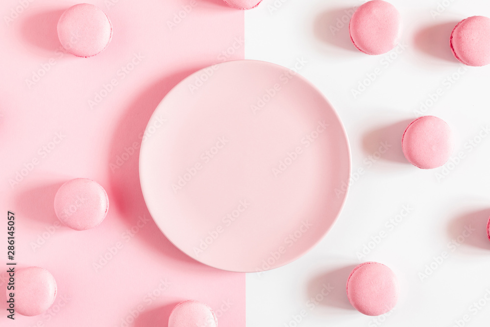 Pink macaroons, empty pink plate on pink and white background. Sweet background. Flat lay, top view, copy space Pink macaroons, empty pink plate on pink and white background. Sweet background. Flat lay, top view, copy space