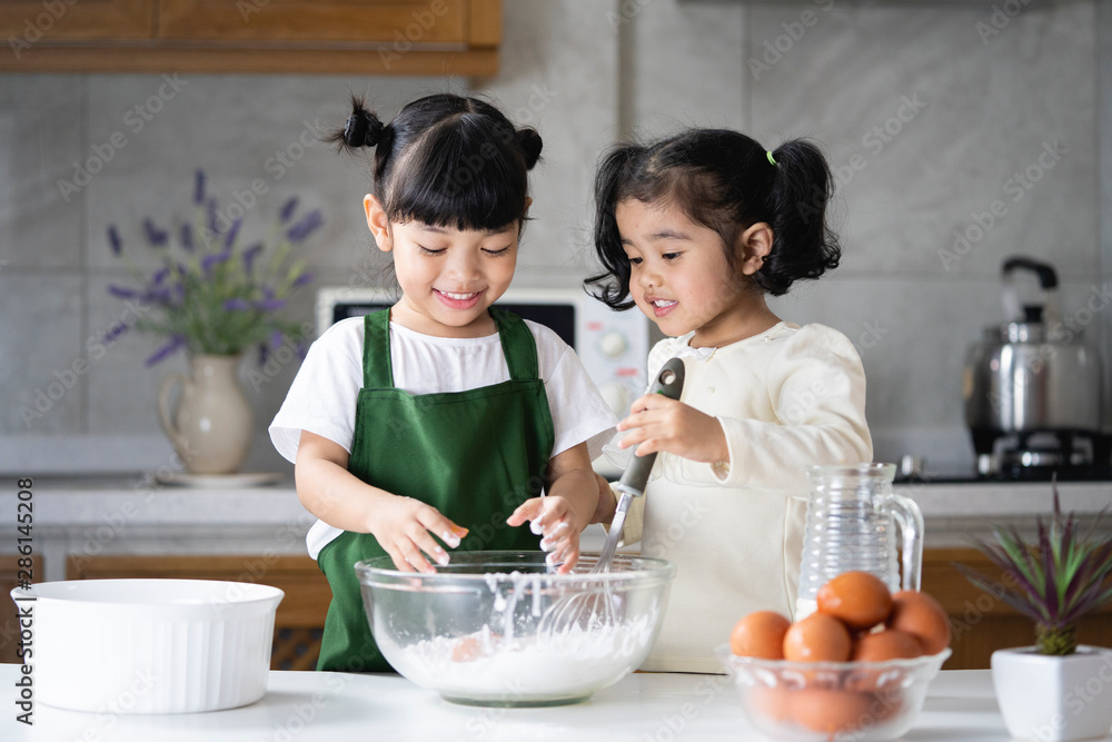 Children enjoy cooking in the kitchen. Happy Asian kids are preparing the dough, bake cookies in the kitchen. Children enjoy cooking in the kitchen. Happy Asian kids are preparing the dough, bake cookies in the kitchen.