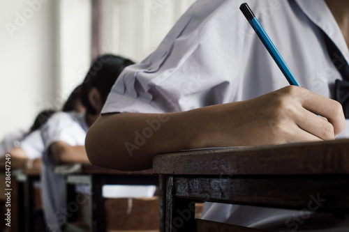 Exam with uniform school student doing educational test with stress in classroom © arrowsmith2