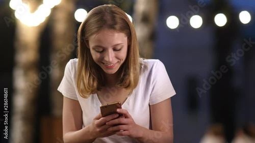 Woman using smart phone at night sitting in cafe outdoars. photo