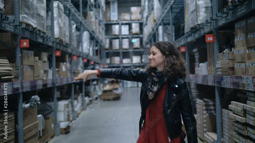 pretty girl dancing a wave with a phone in a large industrial stock room pretty girl dancing a wave with a phone in a large industrial stock room