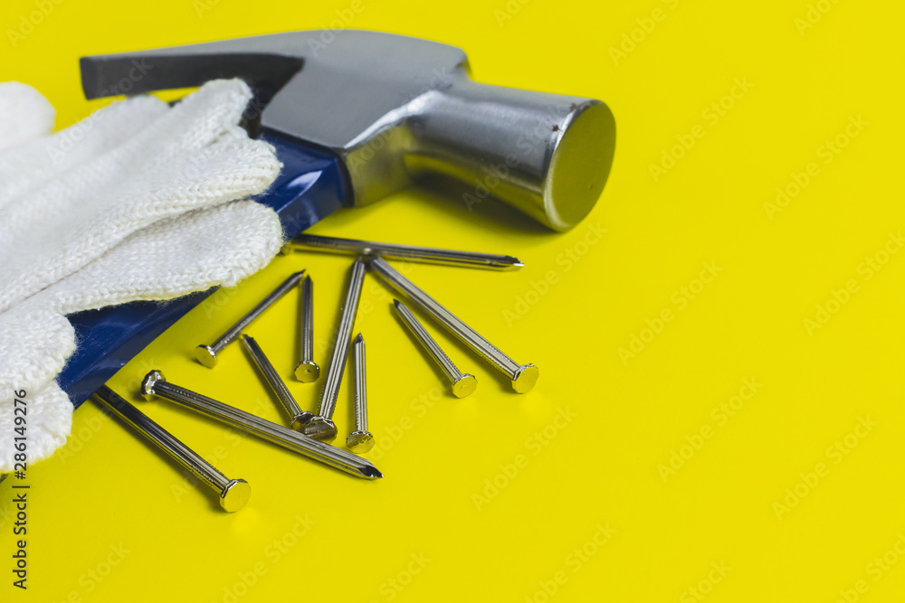 Close up of craftsman tools On a yellow background, hammer, nails, mechanic gloves, top view Close up of craftsman tools On a yellow background, hammer, nails, mechanic gloves, top view