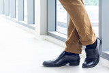 Photos of the legs of men wearing brown pants Black leather shoes Standing in poses Modern office.