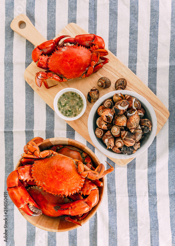 Top view of Steamed Giant Mud Crabs in wooden bowl served with Thai spicy seafood sauce and Grilled Laevistrombus Canarium in shell. photo