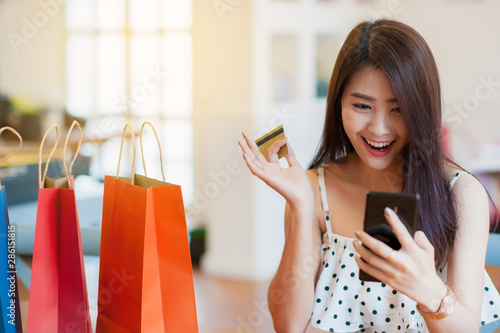 Asian girl shopping online happily.A multicolored paper bag placed next to it.