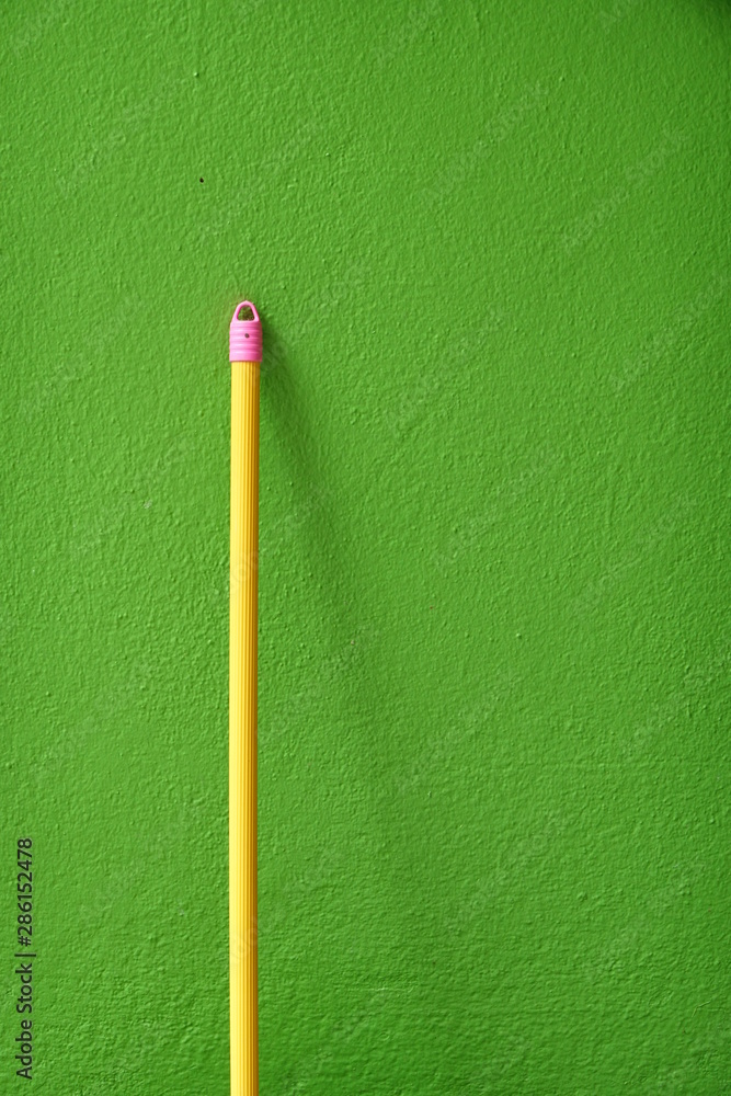 The yellow broom handle on the green wall The yellow broom handle on the green wall