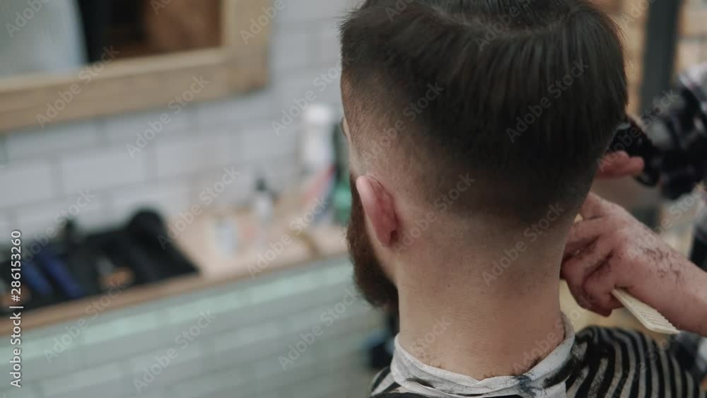 Close-up view on male's hairstyling in a barber shop with professional trimmer. Man's haircutting at hair salon with electric clipper. Grooming the hair. Close-up view on male's hairstyling in a barber shop with professional trimmer. Man's haircutting at hair salon with electric clipper. Grooming the hair.