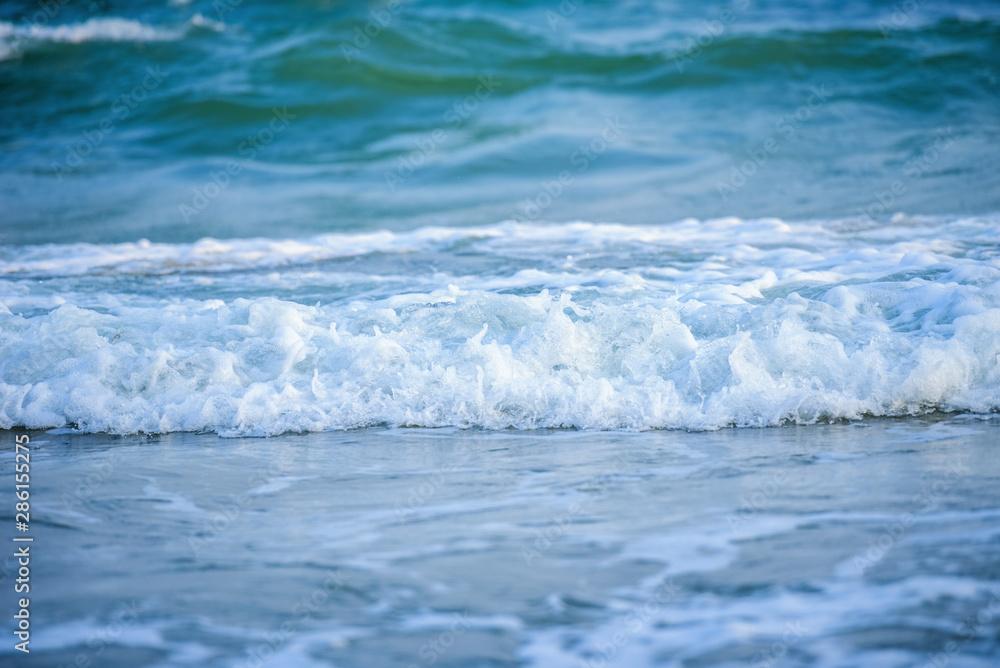 White wave of blue sea on sandy beach.