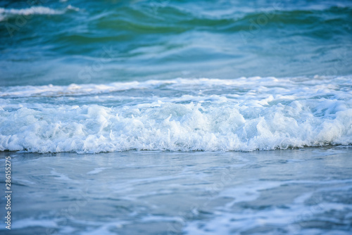 White wave of blue sea on sandy beach.