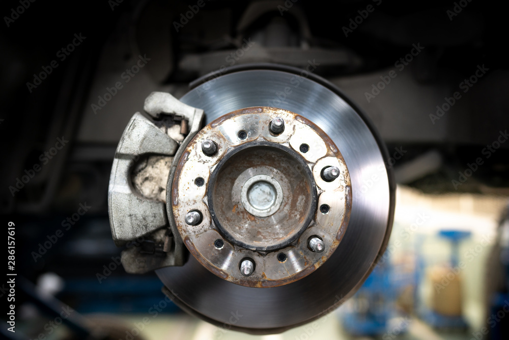 Close up of Brake Disc of the vehicle for repair.Automobile mechanic in process of new tire replacement.Car brake repairing in garage.Car Service and technician concept. Close up of Brake Disc of the vehicle for repair.Automobile mechanic in process of new tire replacement.Car brake repairing in garage.Car Service and technician concept.