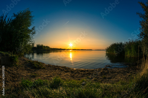 Beach, summer sunset and a blue lake