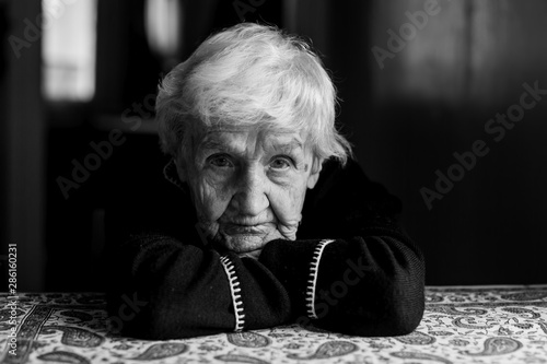 Portrait of old lady in a dark key. Black and white photo.