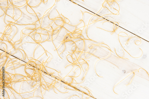 Lot of pieces of thin raw pasta noodles flatlay on white wood
