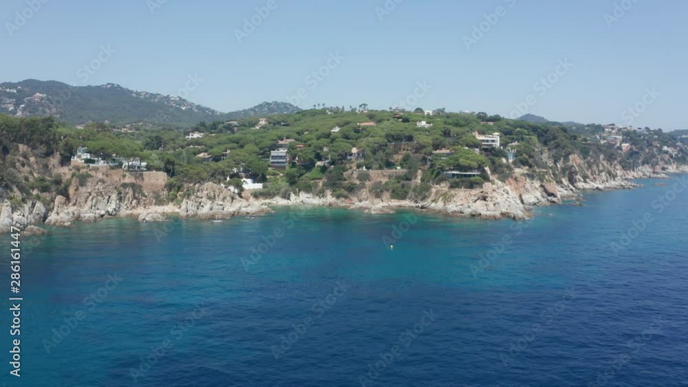 Aerial shot of beautiful deep blue Mediterranean sea and rocky coast near Lloret de Mar resort town on background of green mountains. Drone view of scenic seascape and mountain landscape, Spain Aerial shot of beautiful deep blue Mediterranean sea and rocky coast near Lloret de Mar resort town on background of green mountains. Drone view of scenic seascape and mountain landscape, Spain