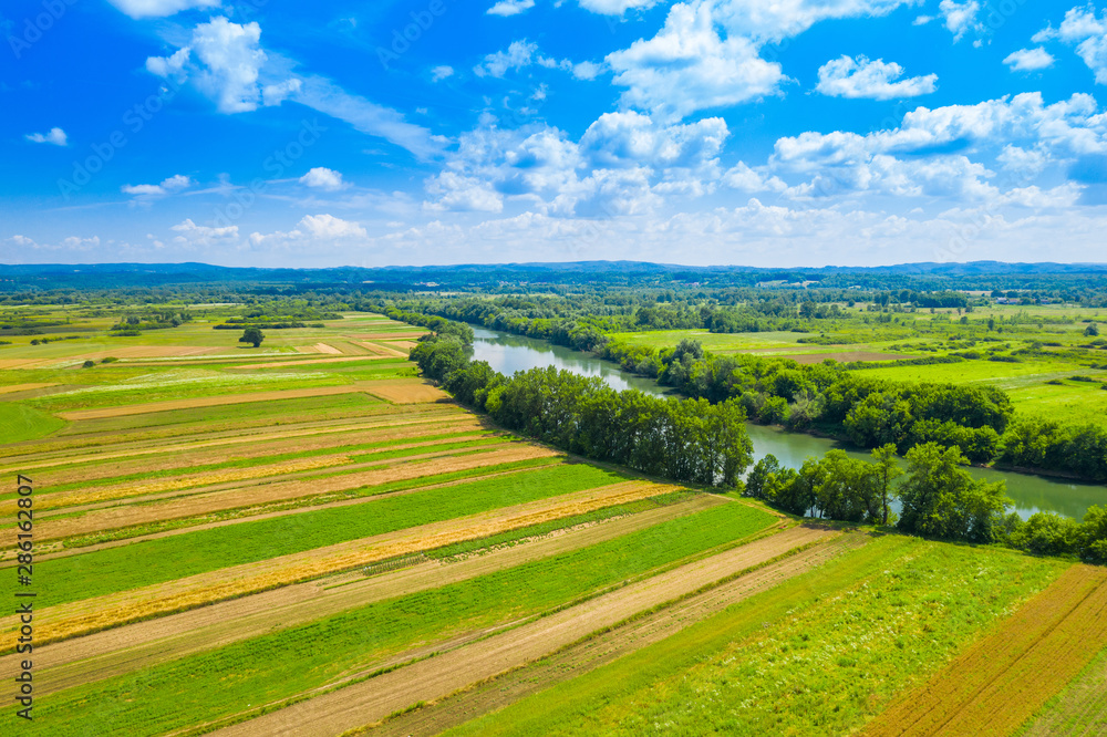 Rural countryside landscape in Croatia, Kupa river meandering between agriculture fields, shot from drone
