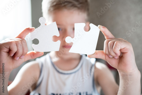 boy is holding a large white puzzle. the child learns to collect puzzles. development, training concept