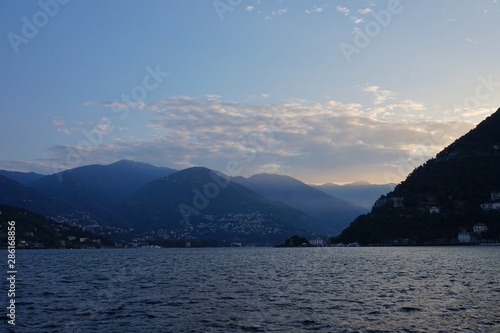 The sun rises over the Alps and Lake Como. View from the promenade of Como.