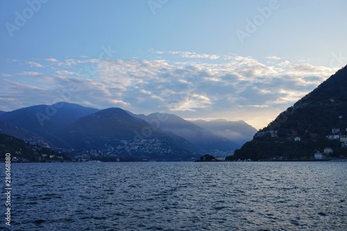 The sun rises over the Alps and Lake Como. View from the promenade of Como.