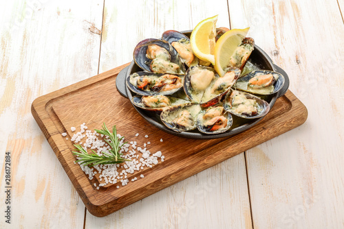 Delicious seafood mussels with with sauce and parsley. Lemon and baguette . Clams in the shells. Top view. photo