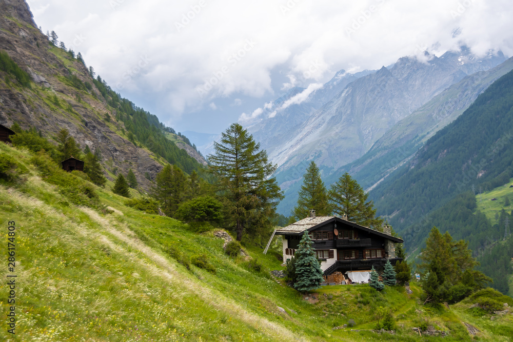 Spectacular summer alpine landscape, mountain swiss wooden chalet with high mountains in background, Zermatt, Switzerland