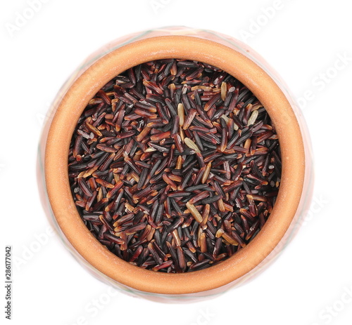 Organic black rice pile in clay pot isolated on white background, top view