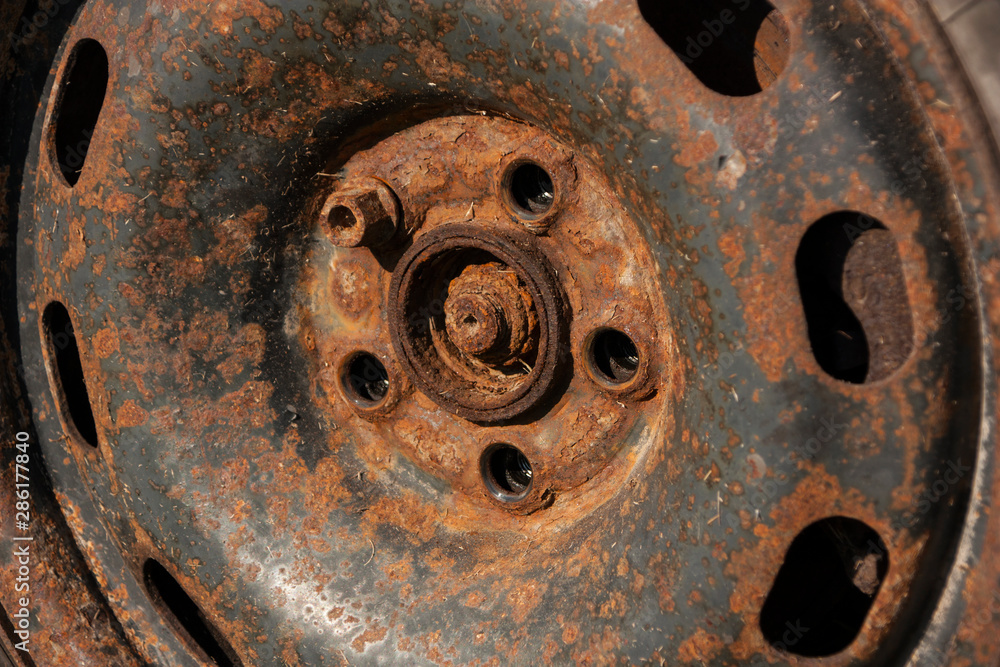 closeup old rusty stamped steel wheel with 1 bolt