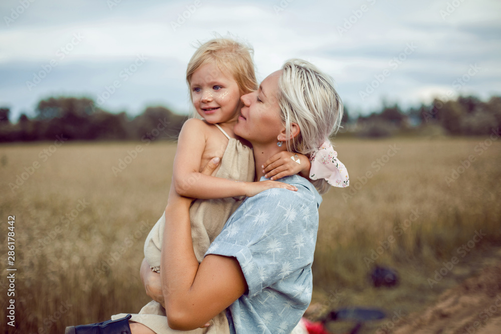 mom holds her daughter in the field with ears of wheat mom holds her daughter in the field with ears of wheat