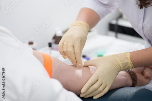 rubber nurse takes blood for analysis with a needle from the patient’s arms