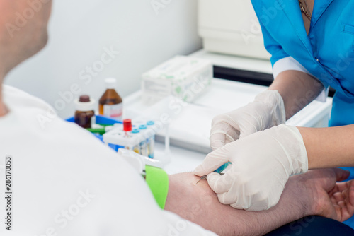 rubber nurse takes blood for analysis with a needle from the patient   s arms