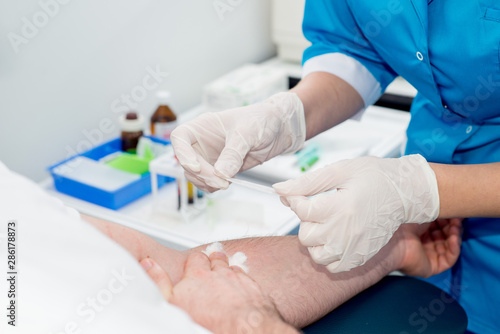 rubber nurse takes blood for analysis with a needle from the patient’s arms