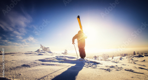 Skier stand mountain top with ski in hands. Winter extreme freeride concept photo