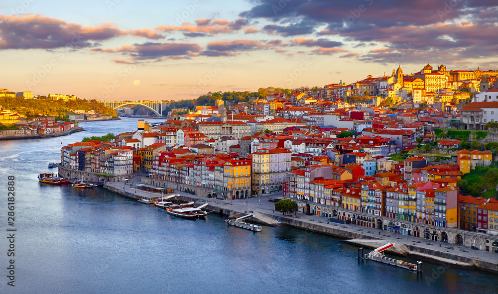 Antique town Porto, Portugal. Sunset sun over silhouettes skyline of roofs of houses along river.